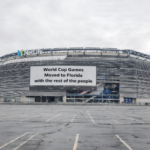 MetLife Stadium exterior with a large billboard reading, "World Cup Games Moved to Florida with the rest of the people."