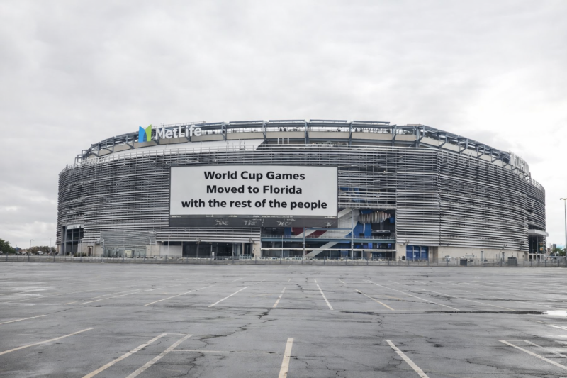 Metlife stadium exterior with a large billboard reading, "world cup games moved to florida with the rest of the people. "