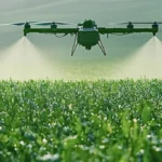 Agricultural drone spraying a green field with mist from its nozzles at ground level