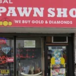Global Pawn Shop storefront with a bright red sign reading 'GLOBAL PAWN SHOP' and 'We Buy Gold & Diamonds' above the entrance; neon 'OPEN' sign in the window.
