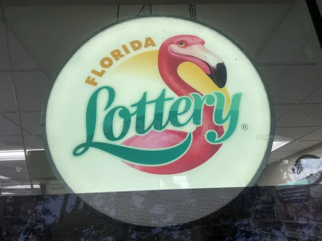 Circular florida lottery sign featuring a pink flamingo and teal 'lottery' text, hanging indoors.