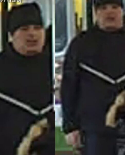 Two men in matching black outfits with white diagonal stripes ride a bus, one wearing a knit cap on the left and the other on the right.