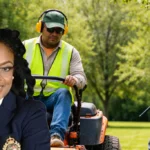 Smiling woman in a dark blazer overlays a park scene where two landscapers in safety vests mow and edge the lawn.