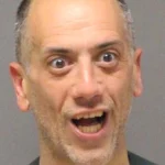 Man with wide eyes and open mouth in a mugshot-style photo, looking surprised or shocked.