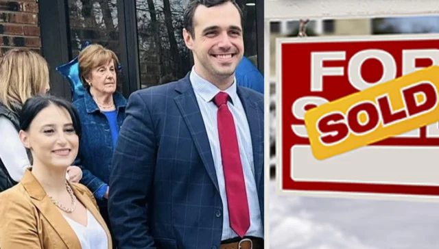 Smiling real estate agents and clients outside a house with a 'for sale' sign and a yellow 'sold' sticker.