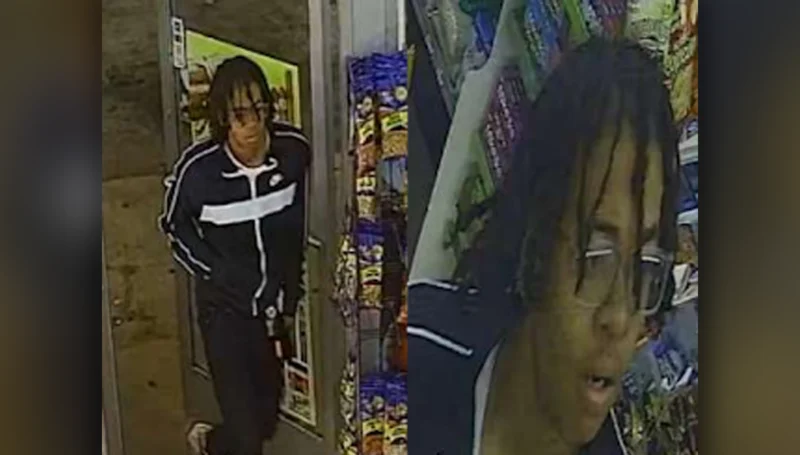 Surveillance image of a man with dreadlocks in a black jacket with a white cross, entering a store.