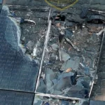 Damaged solar panel array with shattered glass and exposed interior components on a rooftop.