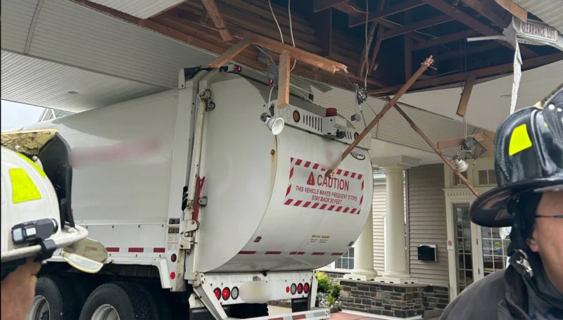 Garbage truck crashes into building overhang in toms river, firefighters deflate tires to free vehicle