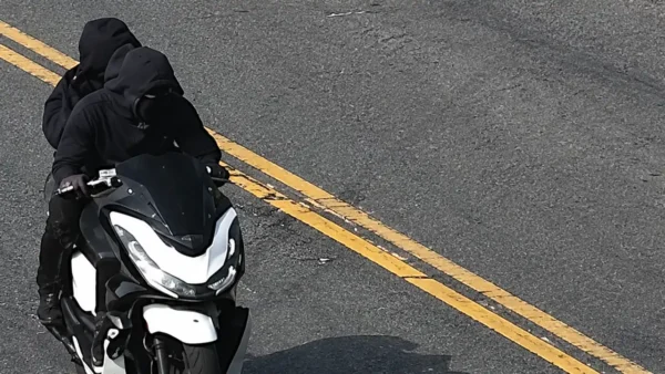 Photo Caption: Surveillance images released by the NYPD show two suspects wanted in connection with a violent necklace robbery involving a black and white moped in the Bronx.