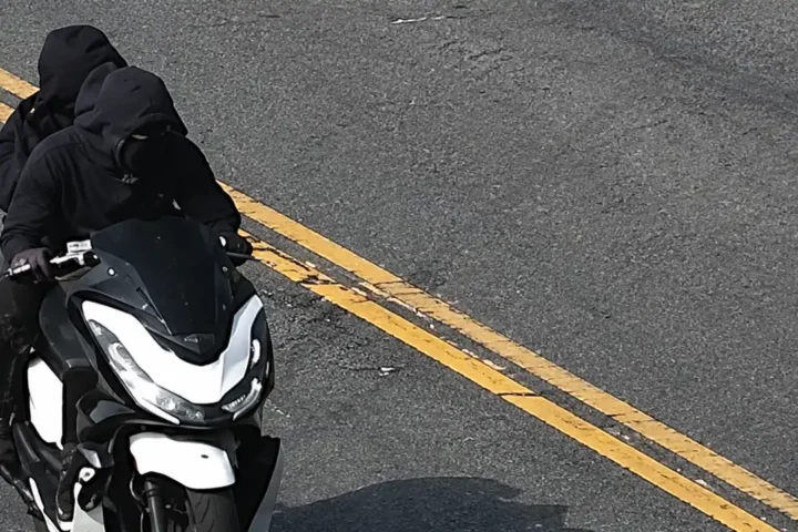 Photo Caption: Surveillance images released by the NYPD show two suspects wanted in connection with a violent necklace robbery involving a black and white moped in the Bronx.