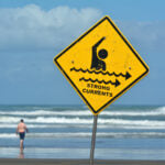 Sign warns of strong currents in the ocean.