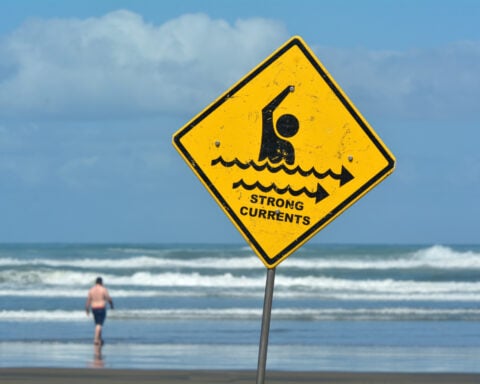 Sign warns of strong currents in the ocean.