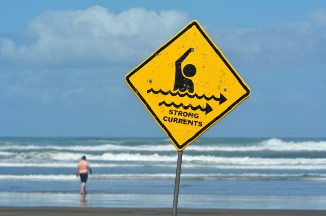 Sign warns of strong currents in the ocean.