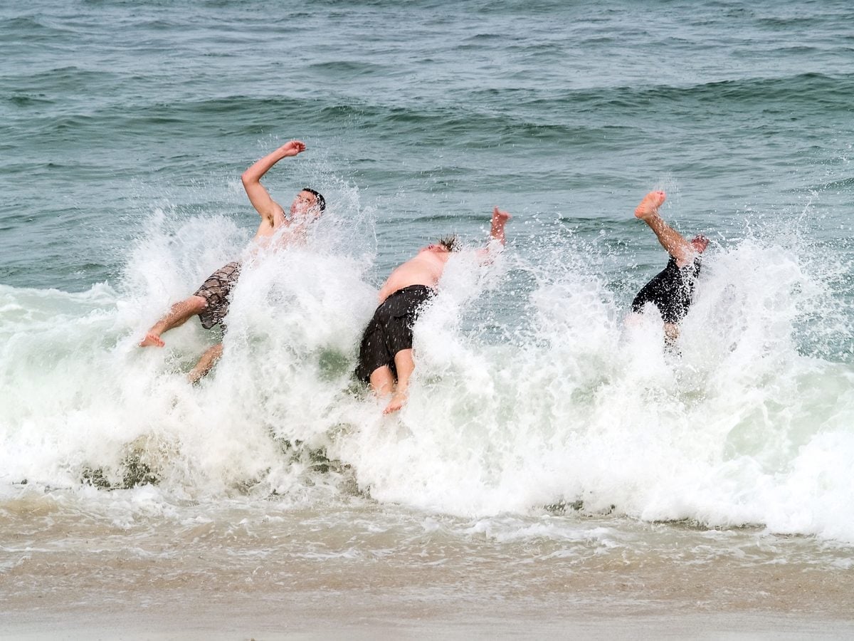 Three college students splash into a breaking wave along the Jersey shore. Photo by Andrew Kazmierski