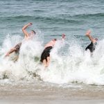 Three college students splash into a breaking wave along the Jersey shore. Photo by Andrew Kazmierski