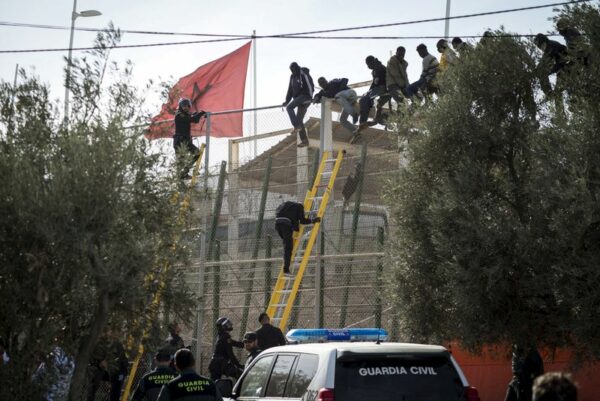 Dozens of migrants piled together at melilla border fence - video