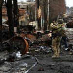 A serviceman uses his mobile phone to film a destroyed