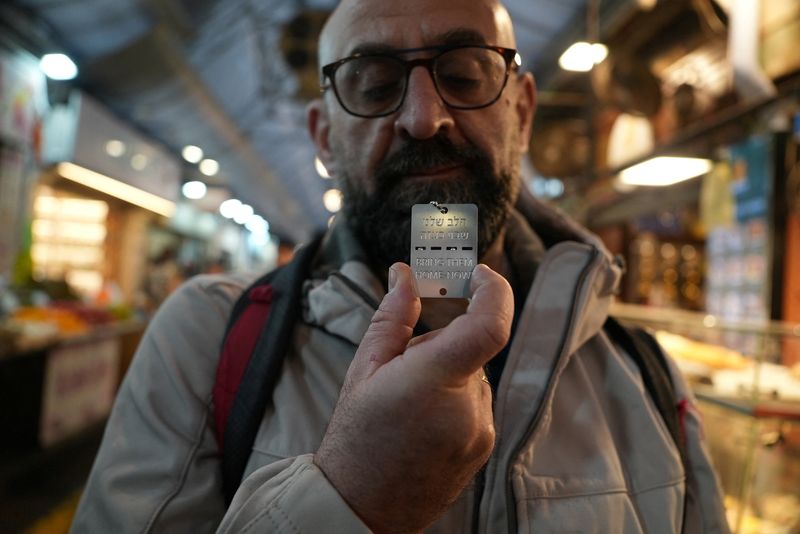 A man holds up a military-style dog tag calling for