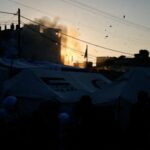Displaced Palestinians react near their tents following an Israeli strike