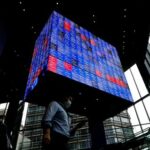 A man walks under an electronic screen showing Japan’s Nikkei