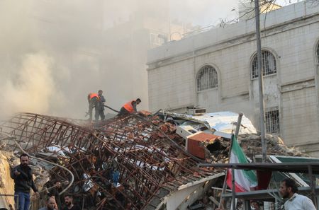 Members of the civil defence stand near a damaged site